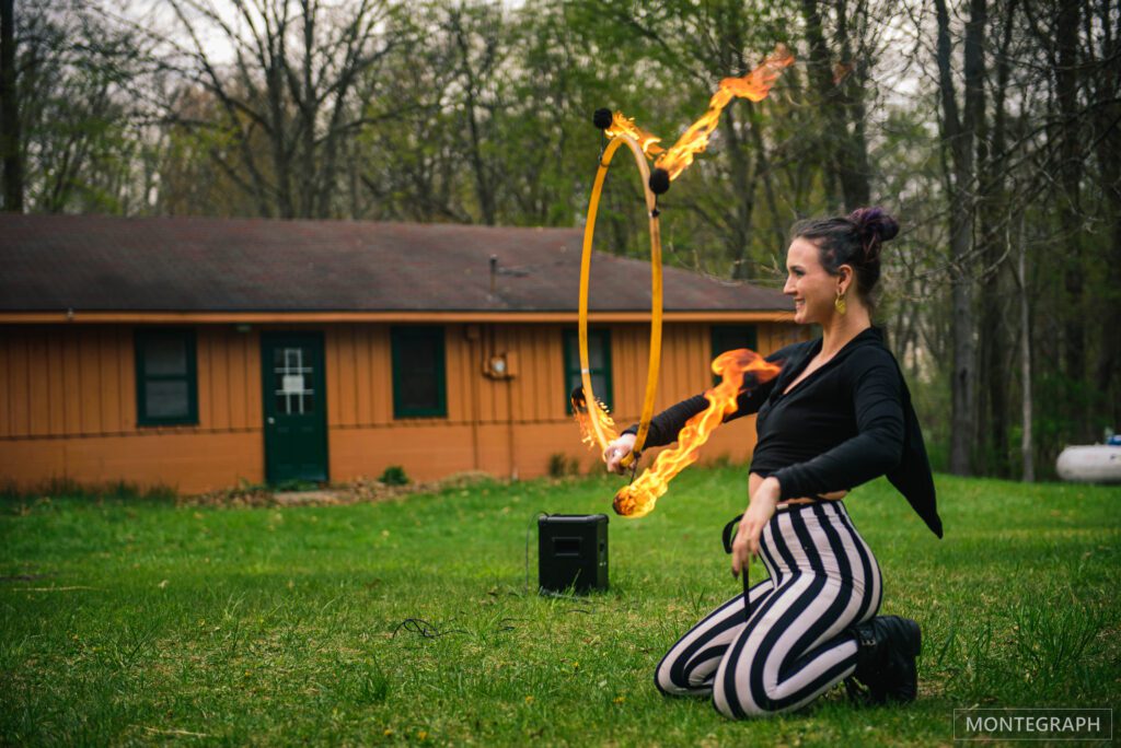 Woman practicing fire poi spinning outdoors.