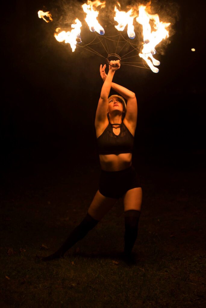 A woman performing a fire dance in the dark.