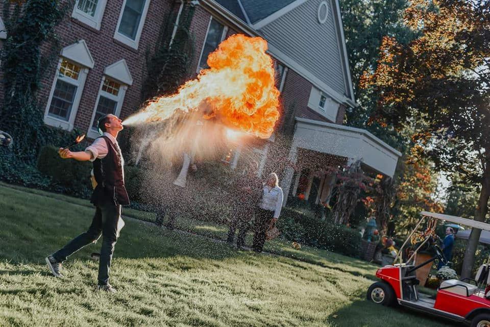 Person breathing fire outdoors in a residential area.