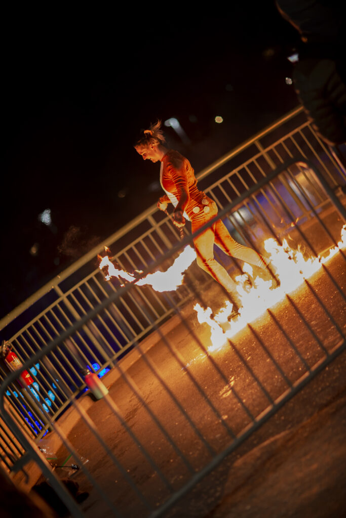A person engulfed in flames standing near a railing at night.