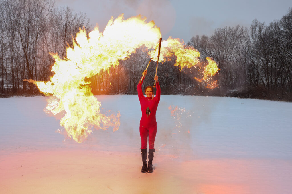 Person in red suit performing fire breathing outdoors.