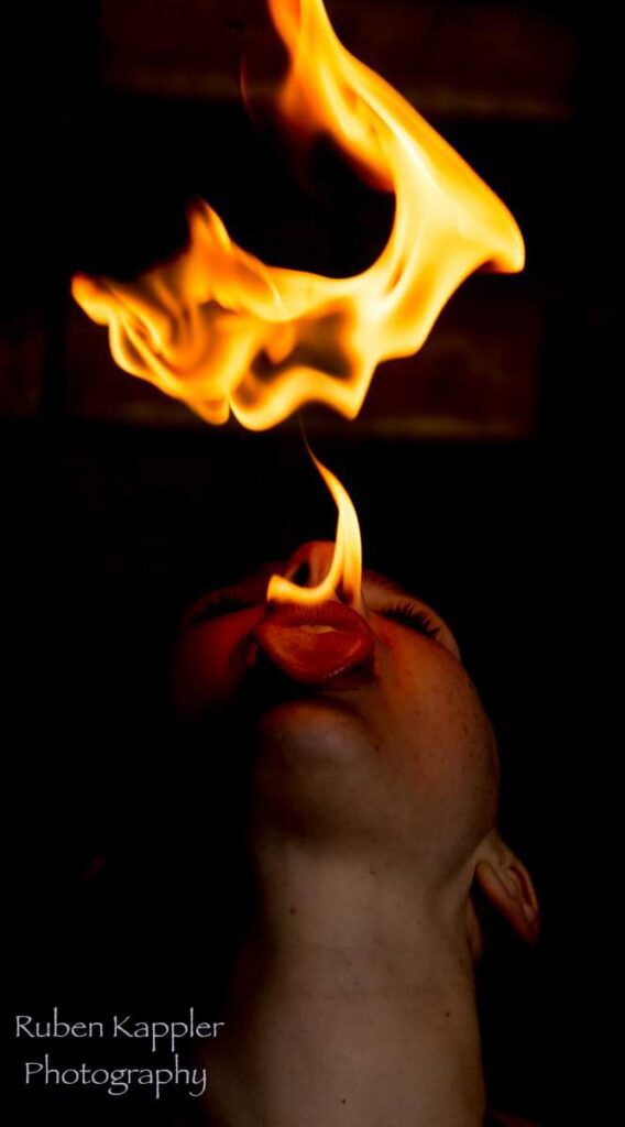 A person breathing fire against a dark background.