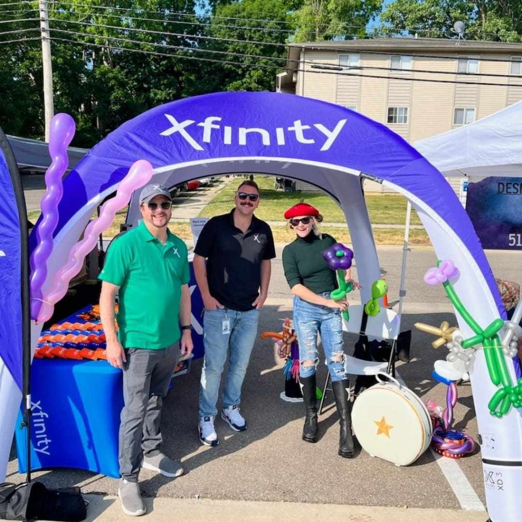 Three people under a purple Xfinity tent with musical instruments.