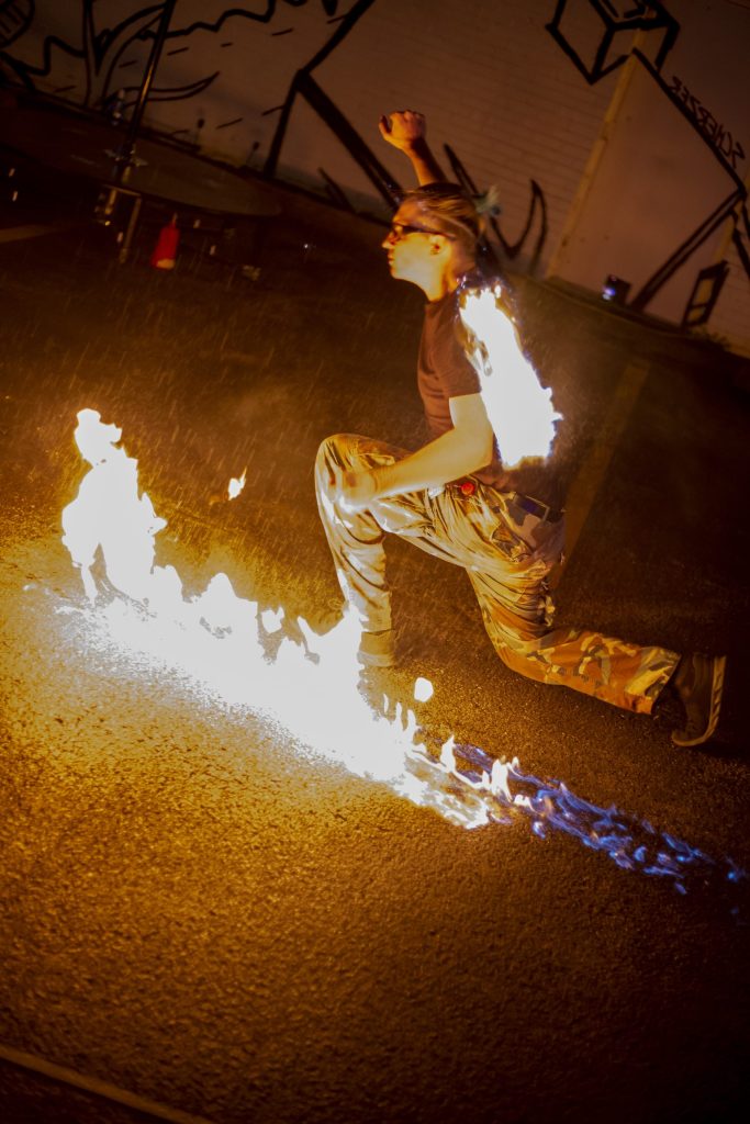 A person performing fire jumping over flames at night.