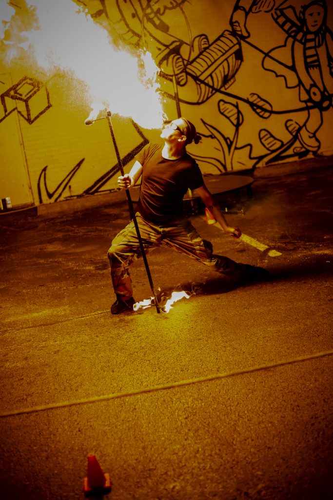 A dancer performs a dramatic pose with a cane in a dimly lit room.