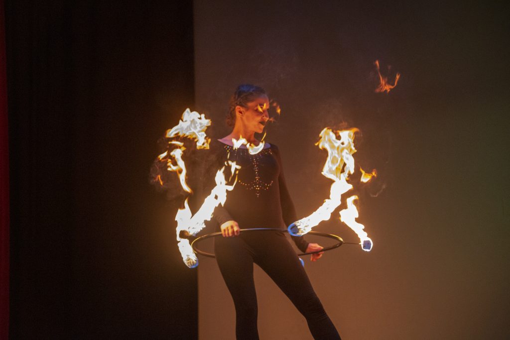 A person performing a fire juggling act in the dark.