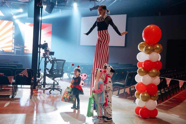 A clown entertaining children at a party with balloons and costumes.
