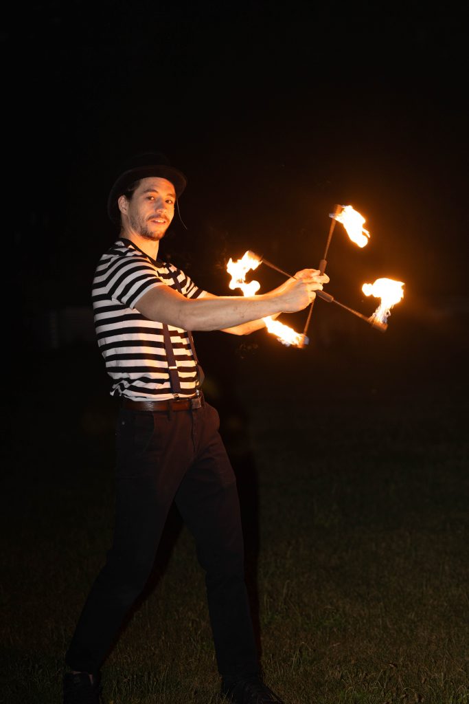 A man spinning fire poi at night.