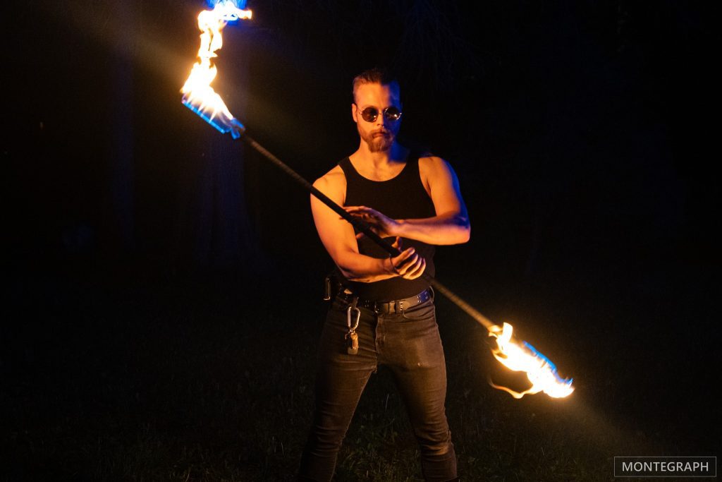 A man spinning fire poi in the dark.