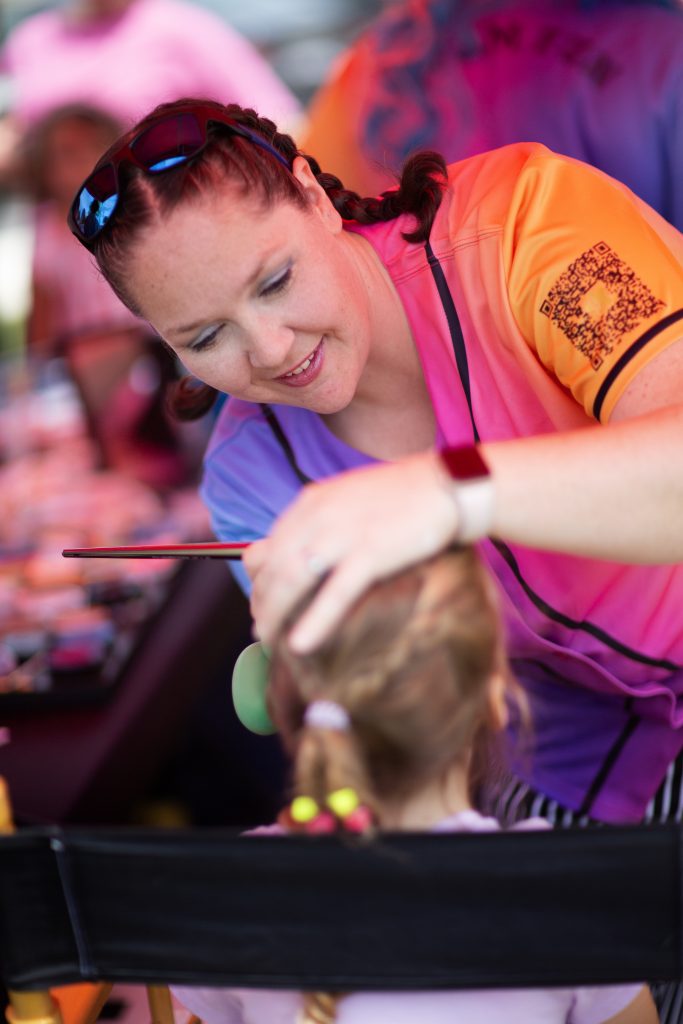 A woman painting a child's face at an event.