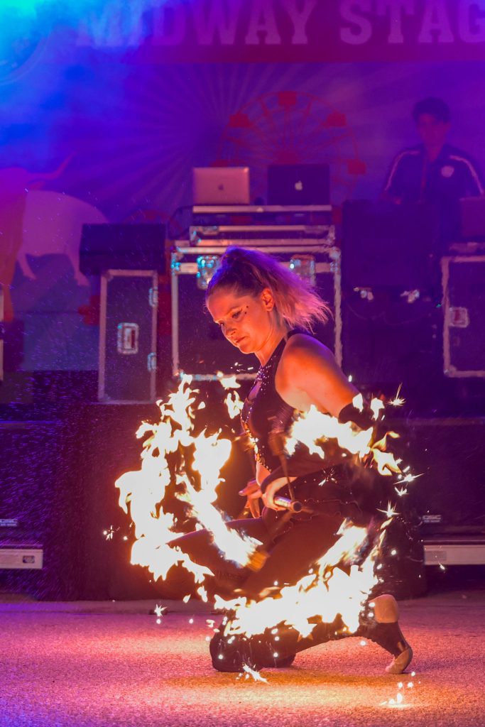 A performer twirls a flaming hoop on stage.