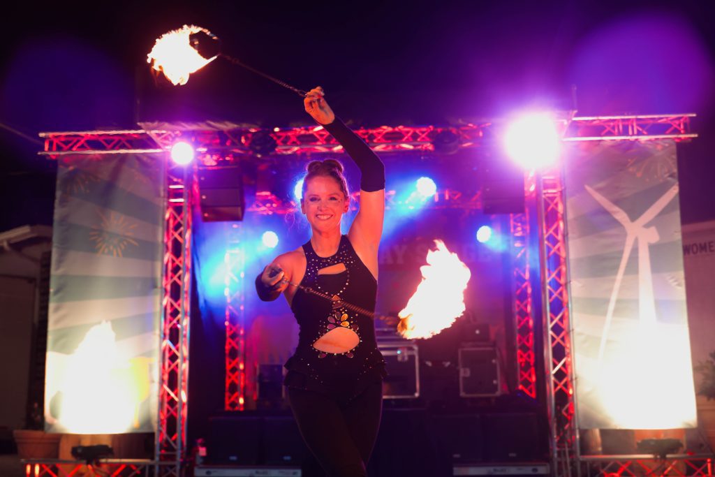 A fire performer dances with flames on stage at night.