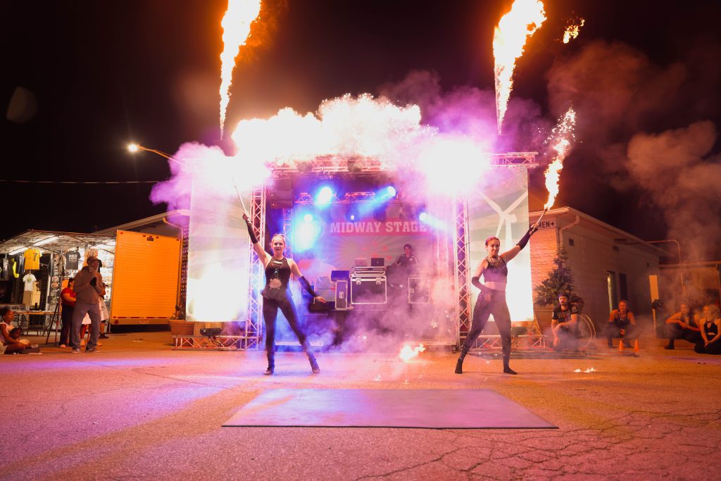 Two performers breathe fire and create flames at night.