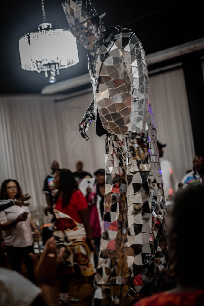 A person wearing a reflective, mosaic-like costume at an indoor event.