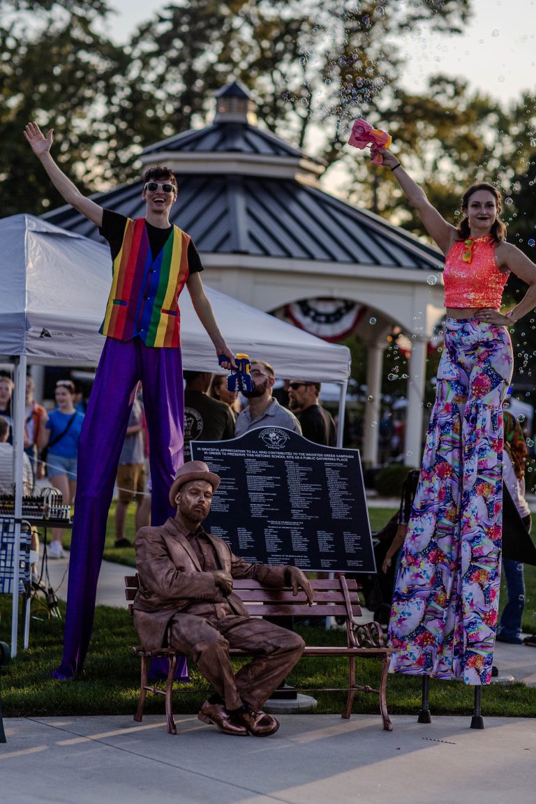 Two performers on stilts in colorful outfits at an outdoor event.