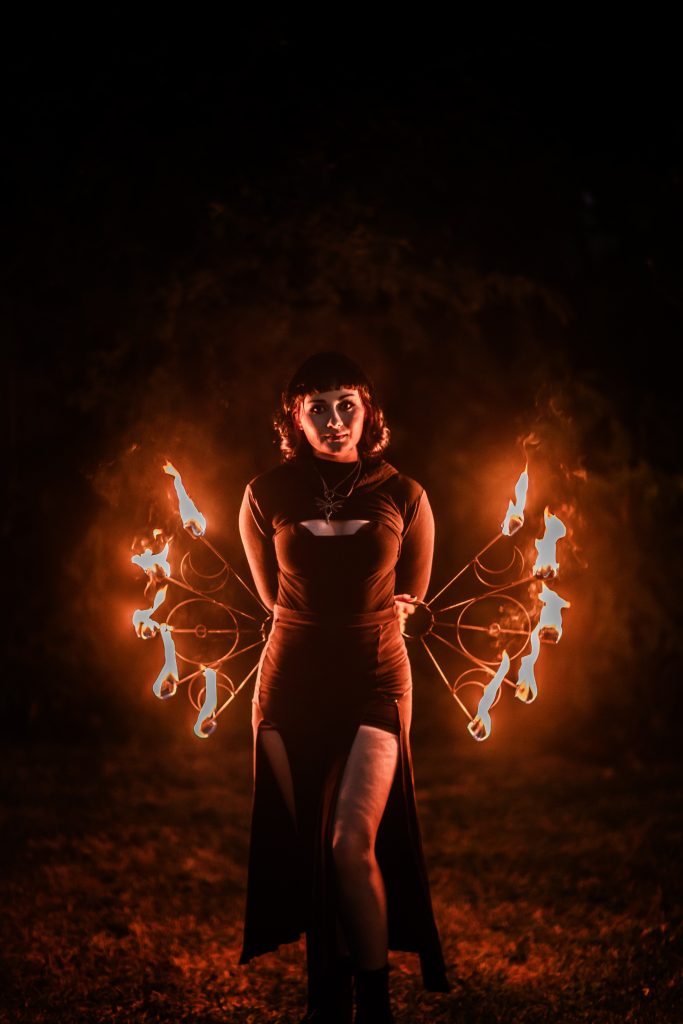 A woman performs with fire fans at night.