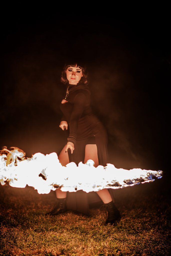 A person performing fire spinning with a staff at night.