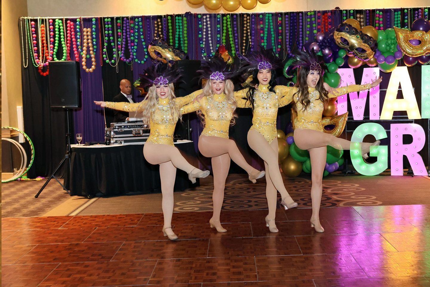 Four performers in gold costumes dancing on stage.