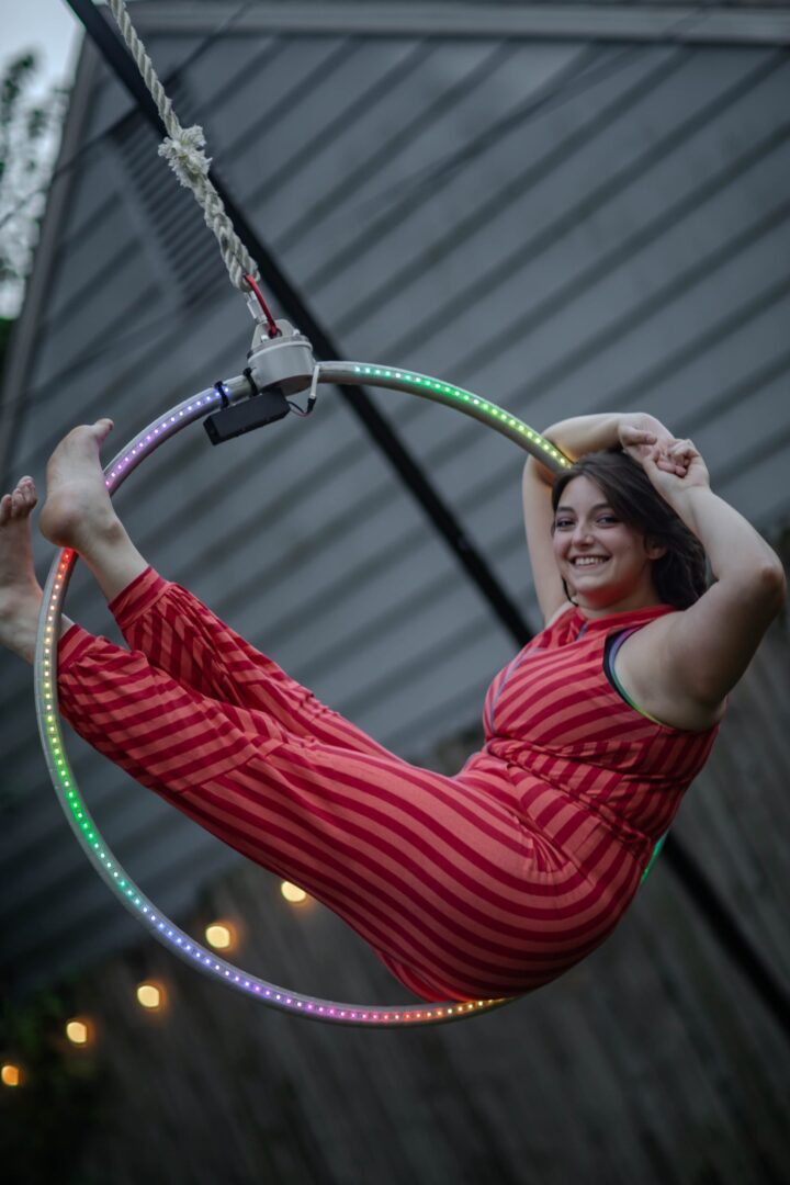 A young girl in red striped pajamas plays with a glowing hula hoop.