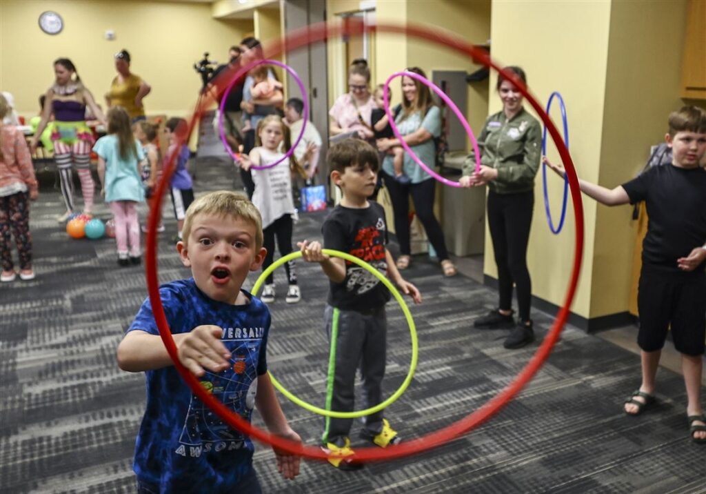 Children playing with colorful hula hoops indoors.