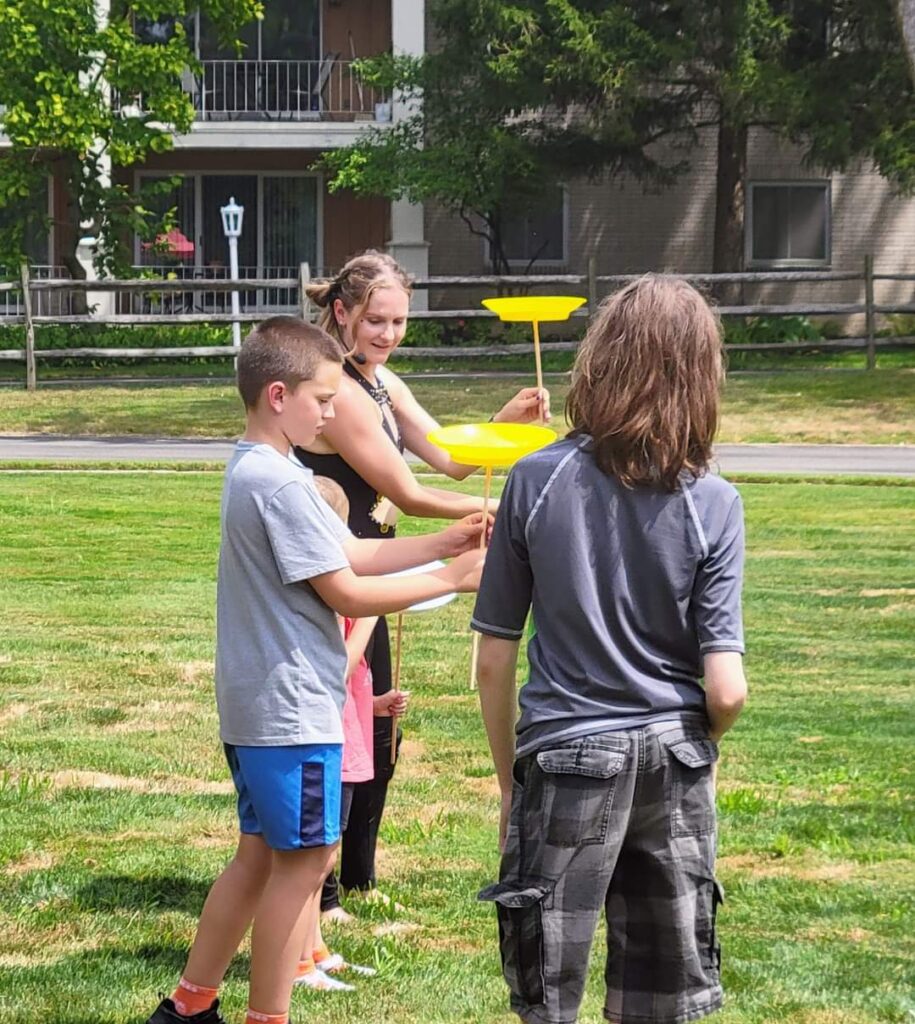 Children playing with spinning plates outdoors.