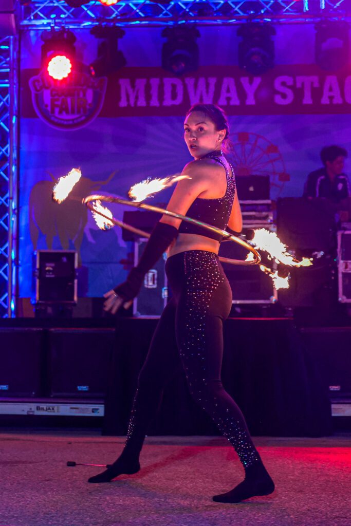 Performer spinning fire hoops on stage.
