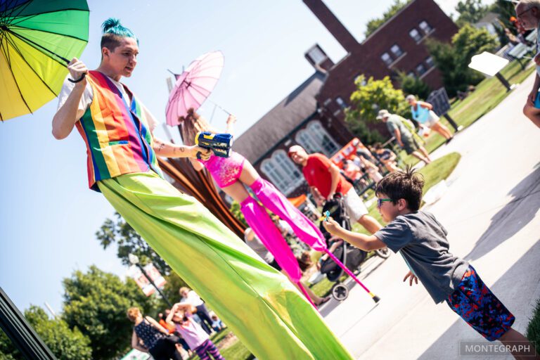 Performer on stilts interacting with excited child.