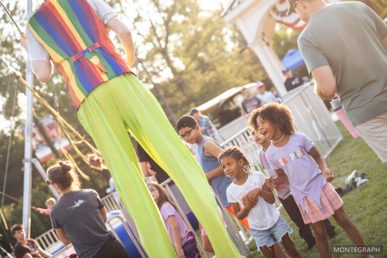 Stilt walker entertaining children at outdoor event.