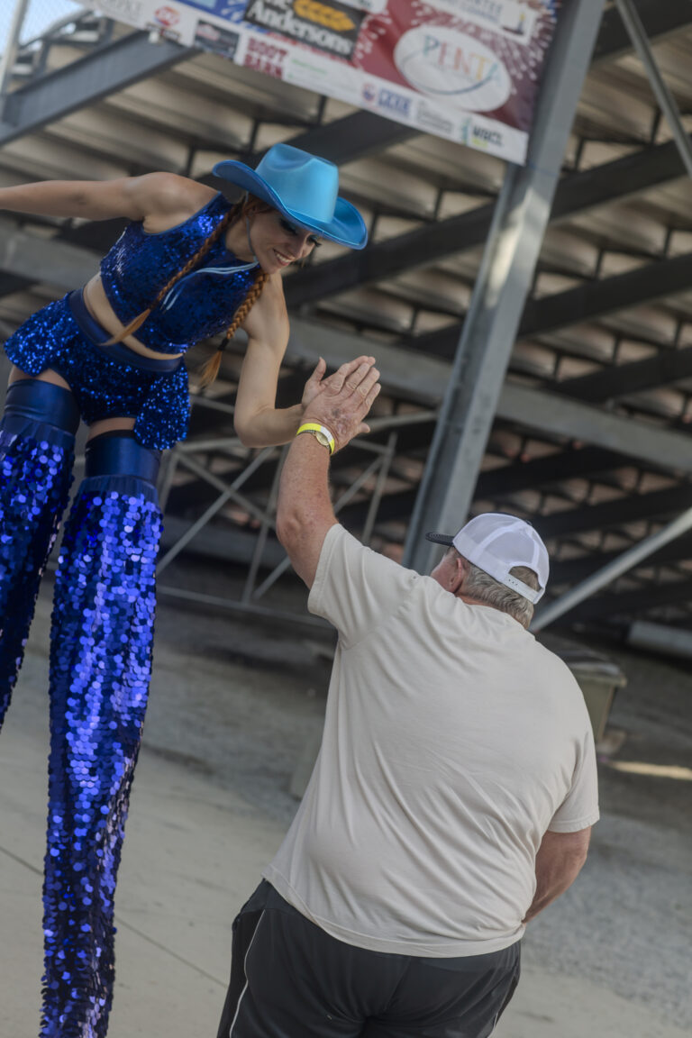 Performer on stilts high-fiving a man.