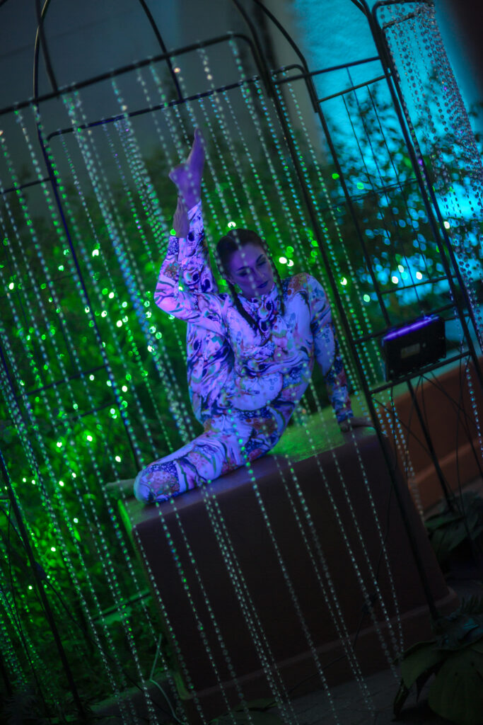 Contortionist performing inside illuminated beaded cage