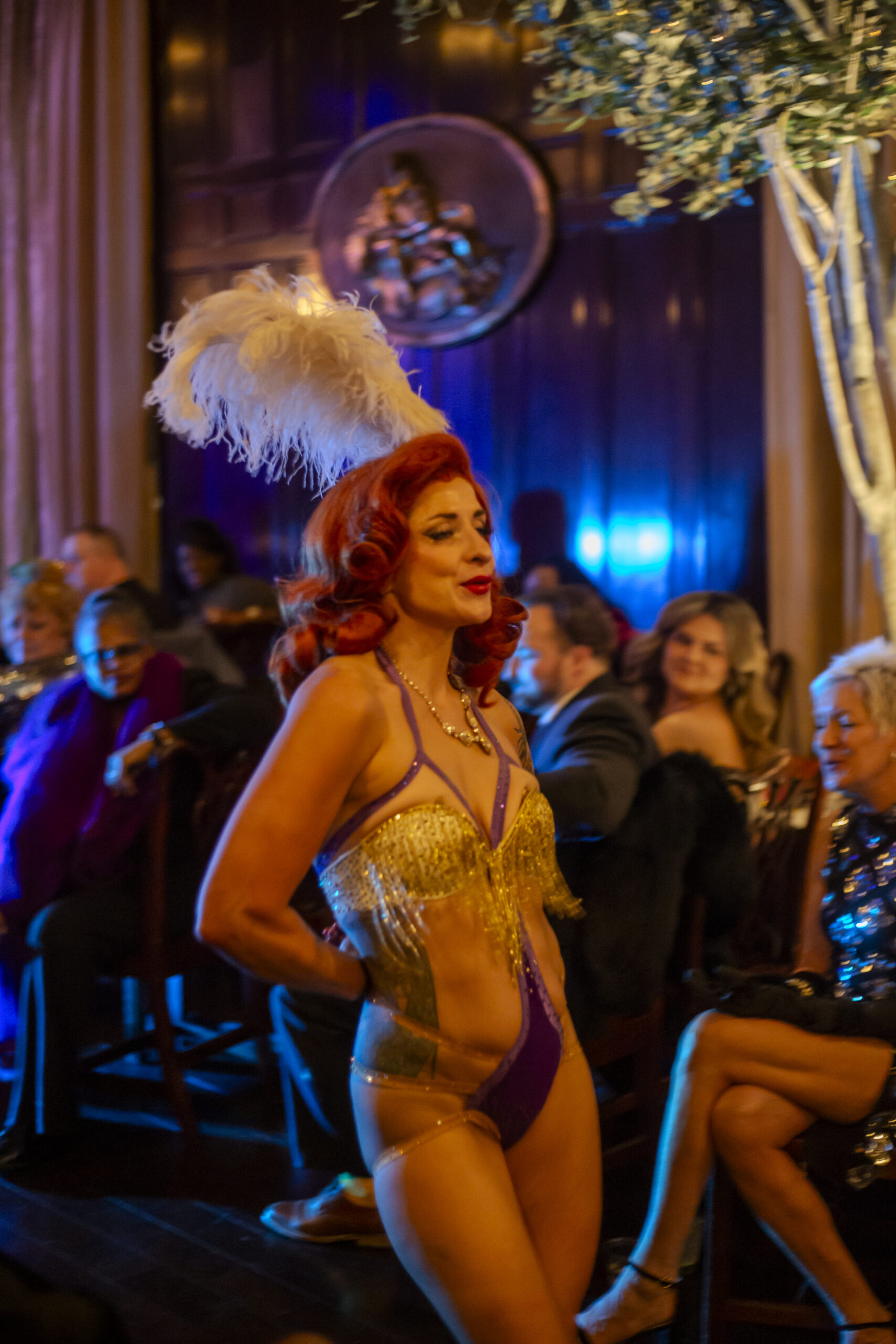 Burlesque performer in gold fringe and feathers