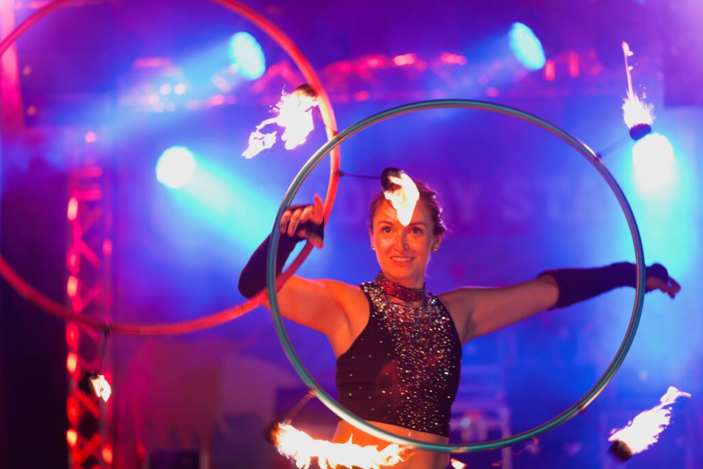 Flaming hula-hoop performer on colorful stage