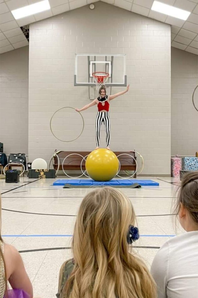 Circus performer balancing on giant yellow ball