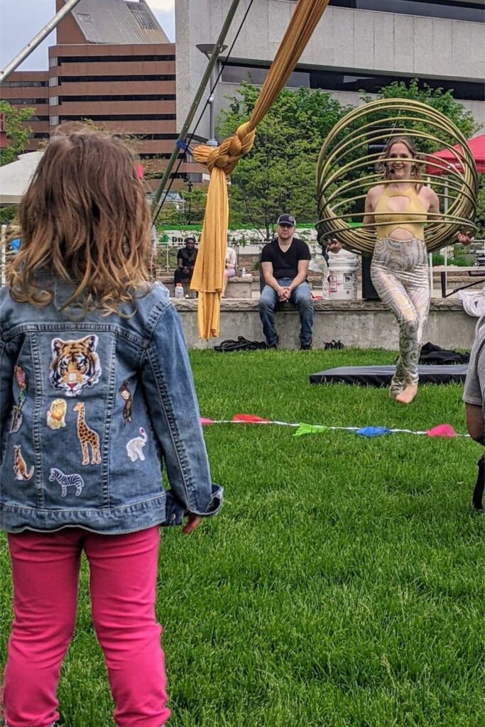 Child watches aerial hoop performer in park