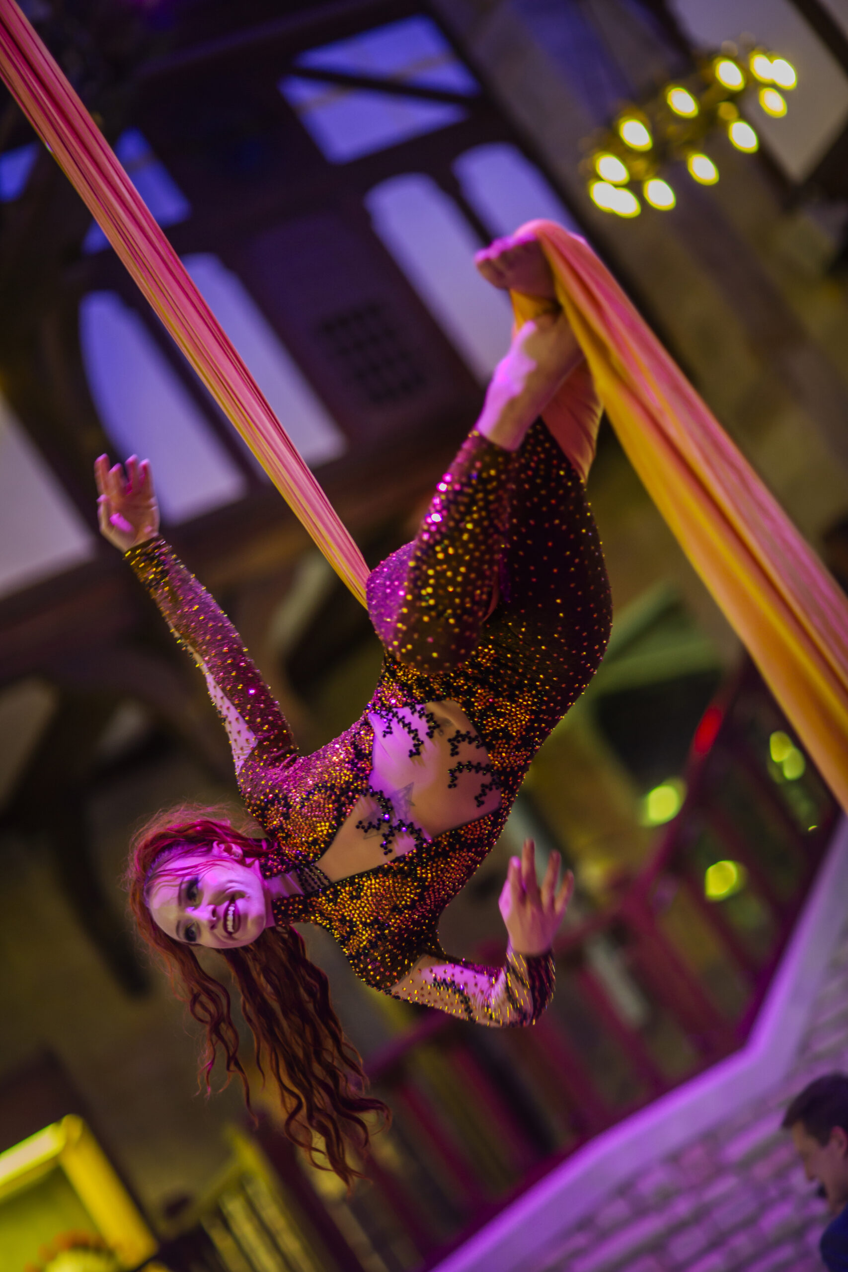 Upside-down aerial silk performer in sequined costume