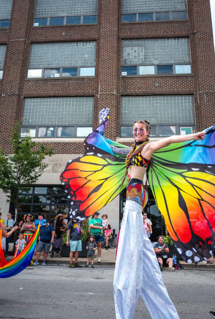 Stilt performer with rainbow butterfly wings at parade