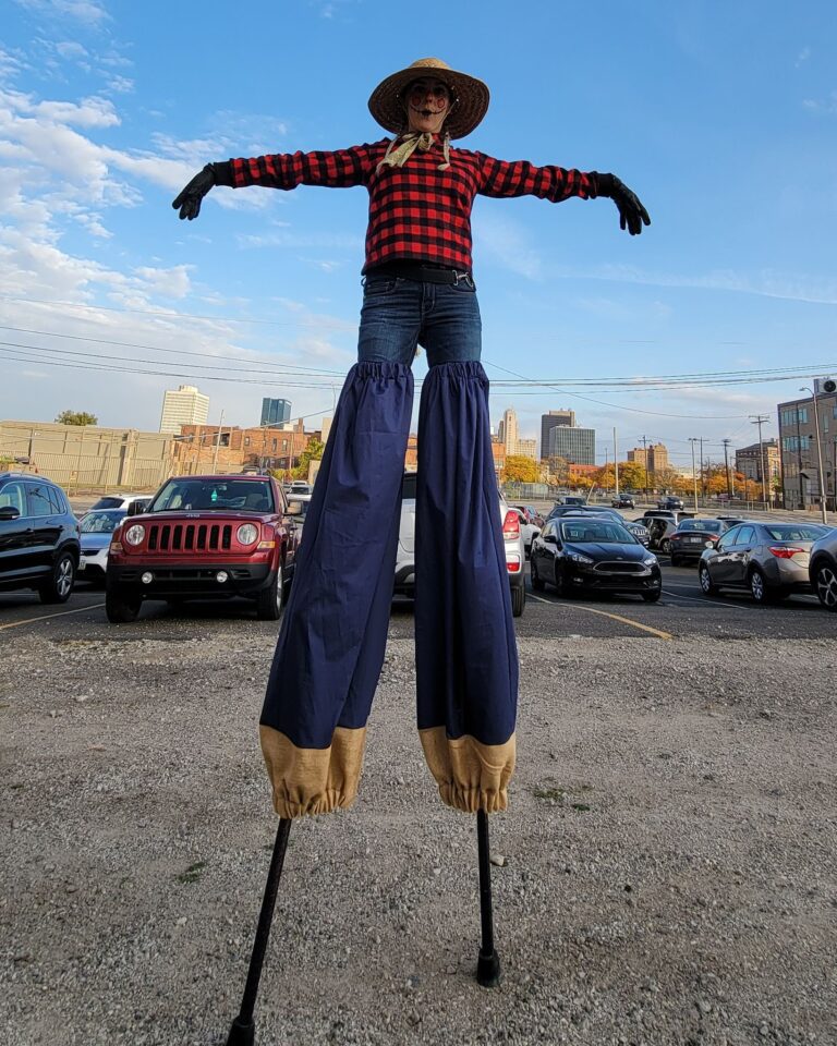 Stilt-walking scarecrow in parking lot
