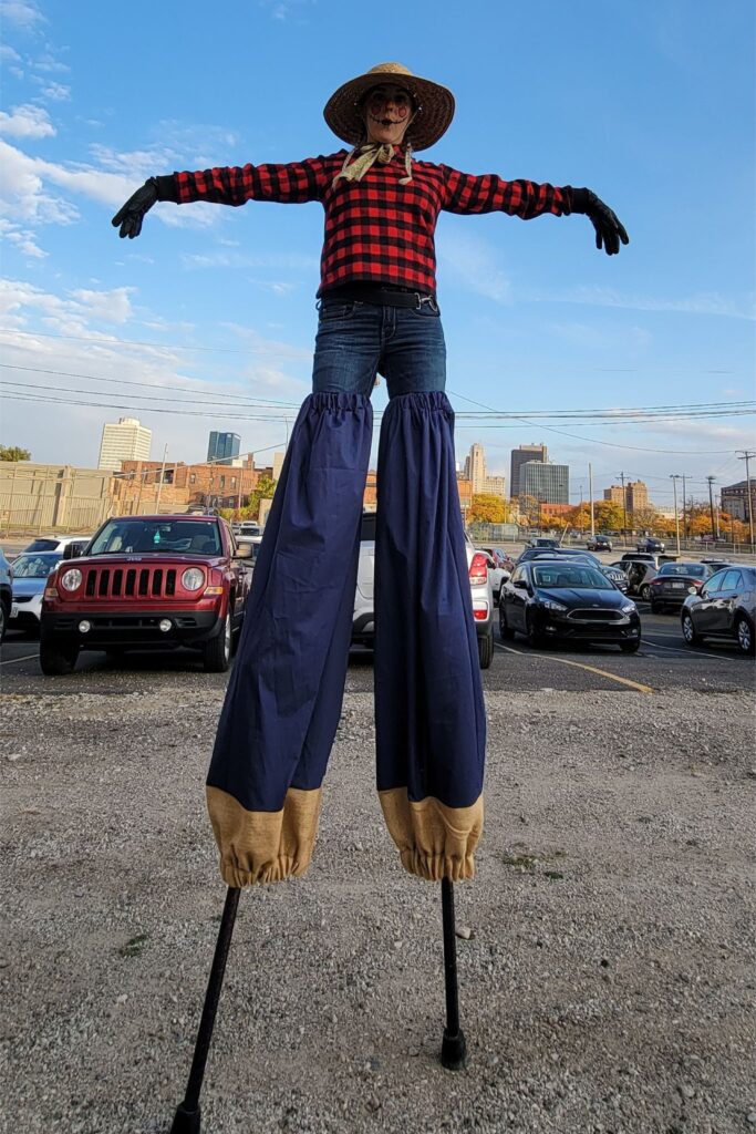 Stilt-walking performer in plaid and straw hat