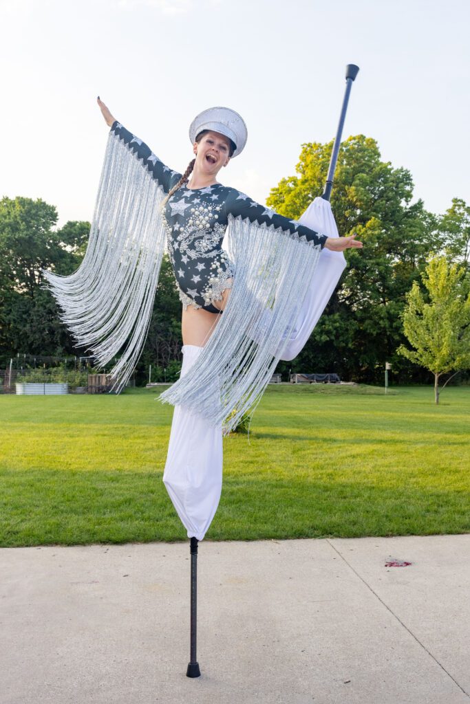 Smiling stilt performer in silver fringe costume