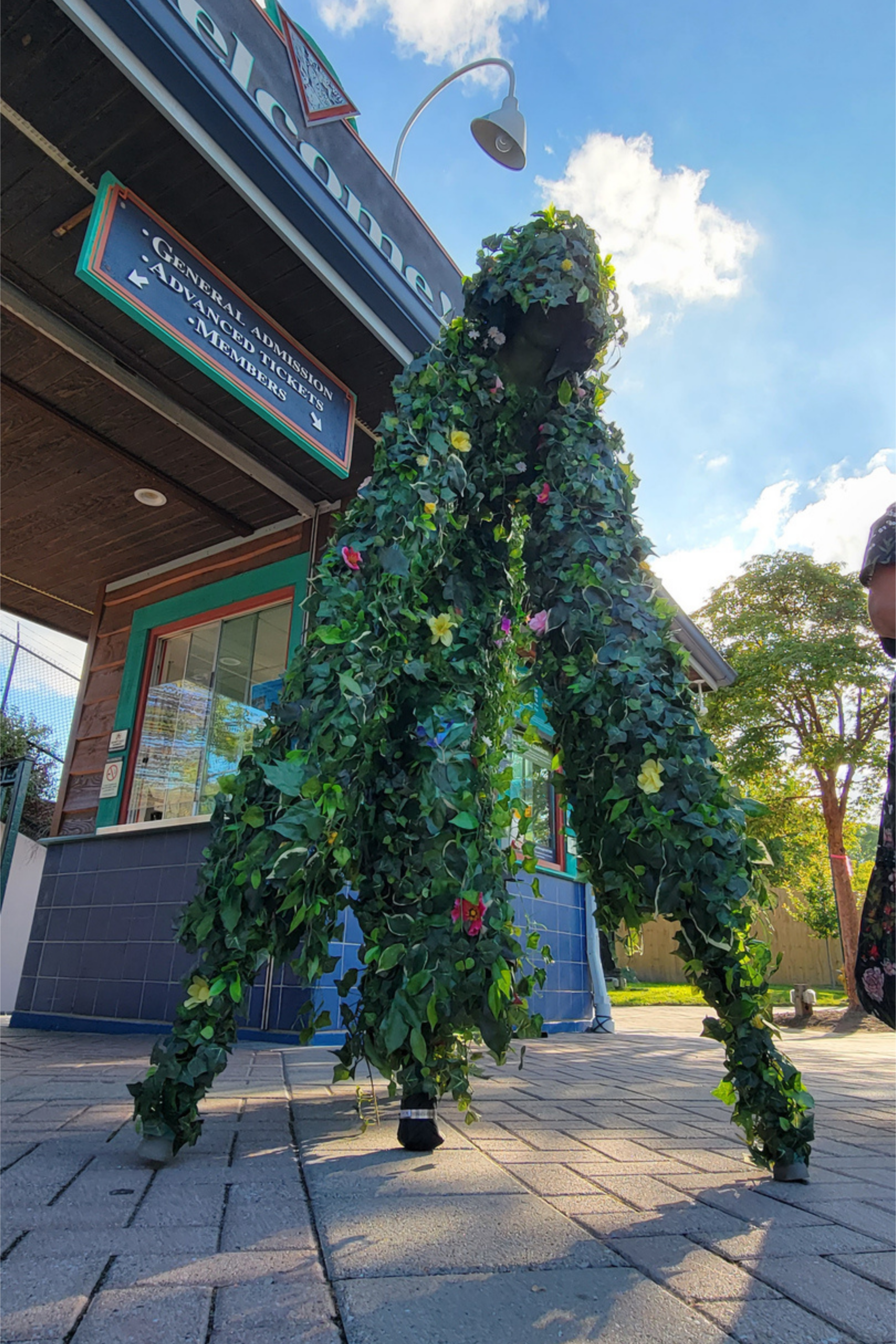 Tall stilt-walker covered in green foliage