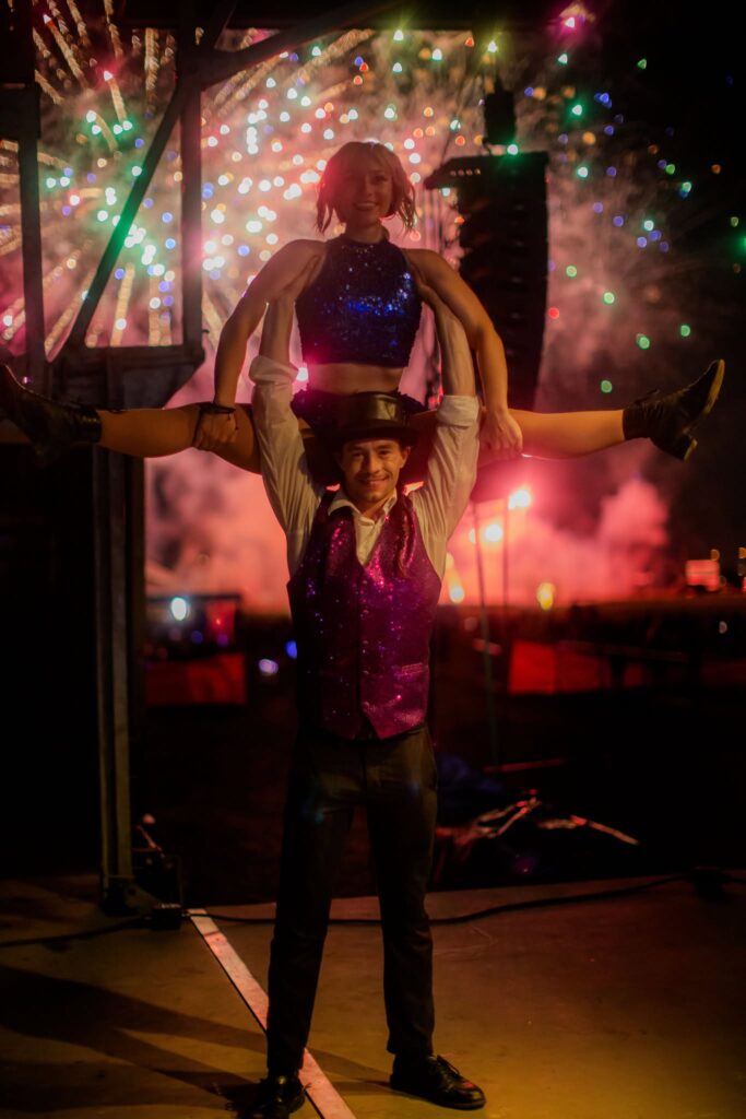 Acrobatic duo lifts dancer amid colorful fireworks