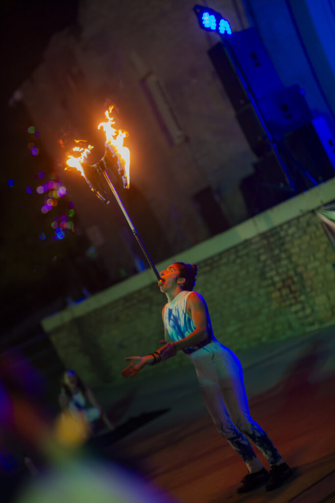 Fire breather balancing flaming torches at night