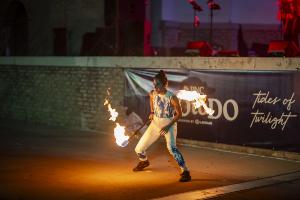 Performer twirling flaming torches on outdoor stage