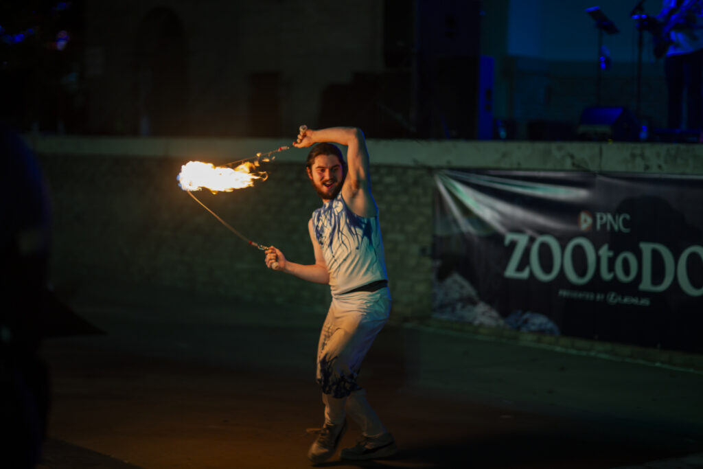 Fire performer twirling flaming staff at night
