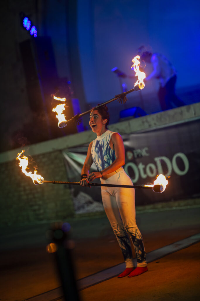 Smiling fire performer juggling flaming staffs