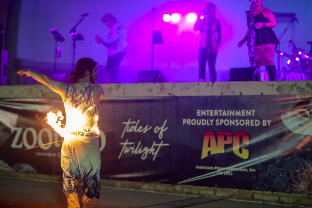 Fire dancer performing before illuminated stage band