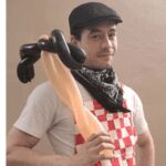 Man holding a balloon sculpture in costume.