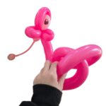 "Hand holding a pink balloon animal creation."